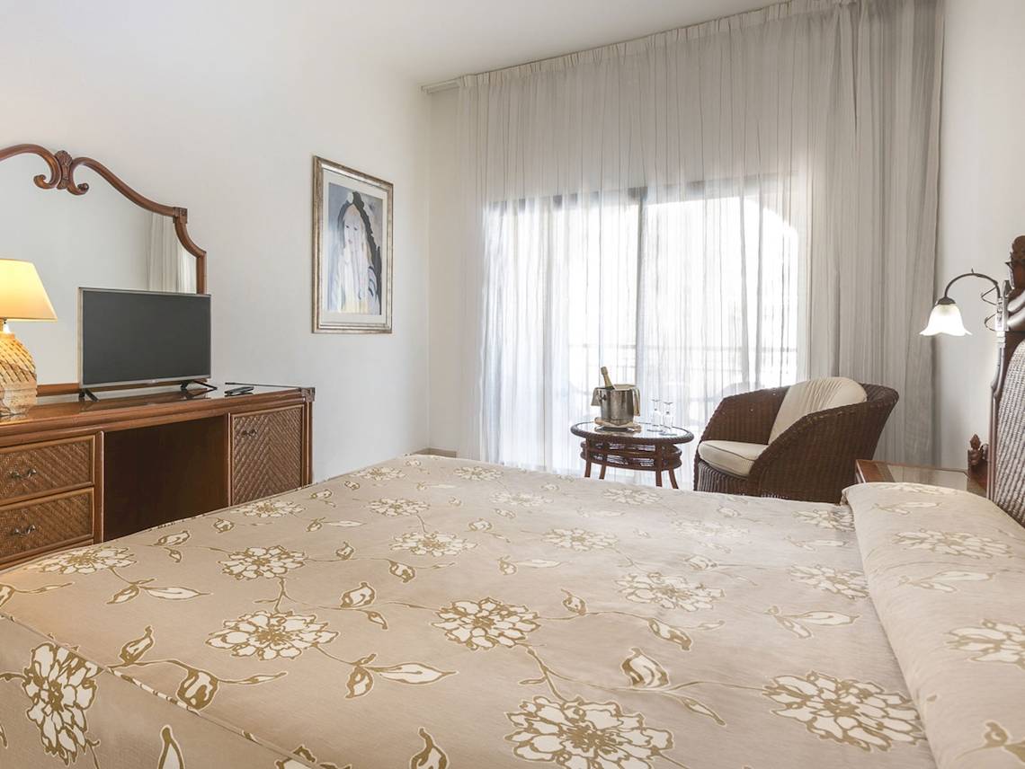 Schlafzimmer im Princess Inspire Tenerife Hotel mit Bett, Fernseher, Spiegel, und Tisch mit Weinflasche.