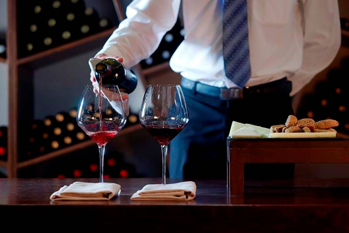 Kellnerin gießt Rotwein in zwei Gläser auf dem Royal Blue Resort