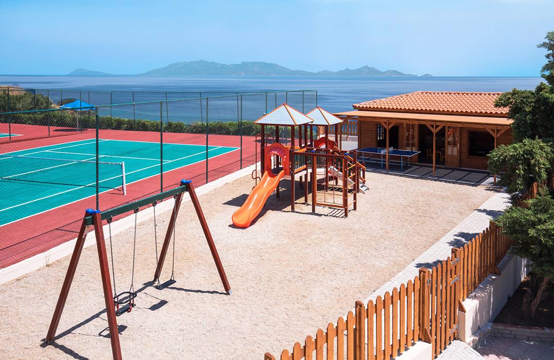 Außenbereich des Mitsis Summer Palace Beach Hotels mit Spielplatz und Tennisplatz am Meer