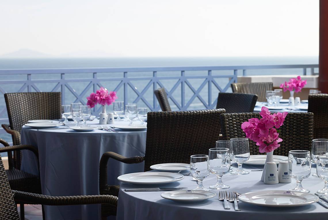 Tisch auf der Terrasse des Mitsis Summer Palace Beach Hotels mit Blick auf das Meer.
