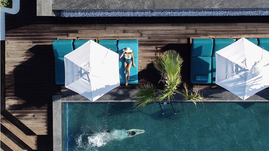 Luftaufnahme des Pools im Mitsis Summer Palace Beach Hotel mit Liegen und Sonnenschirmen.