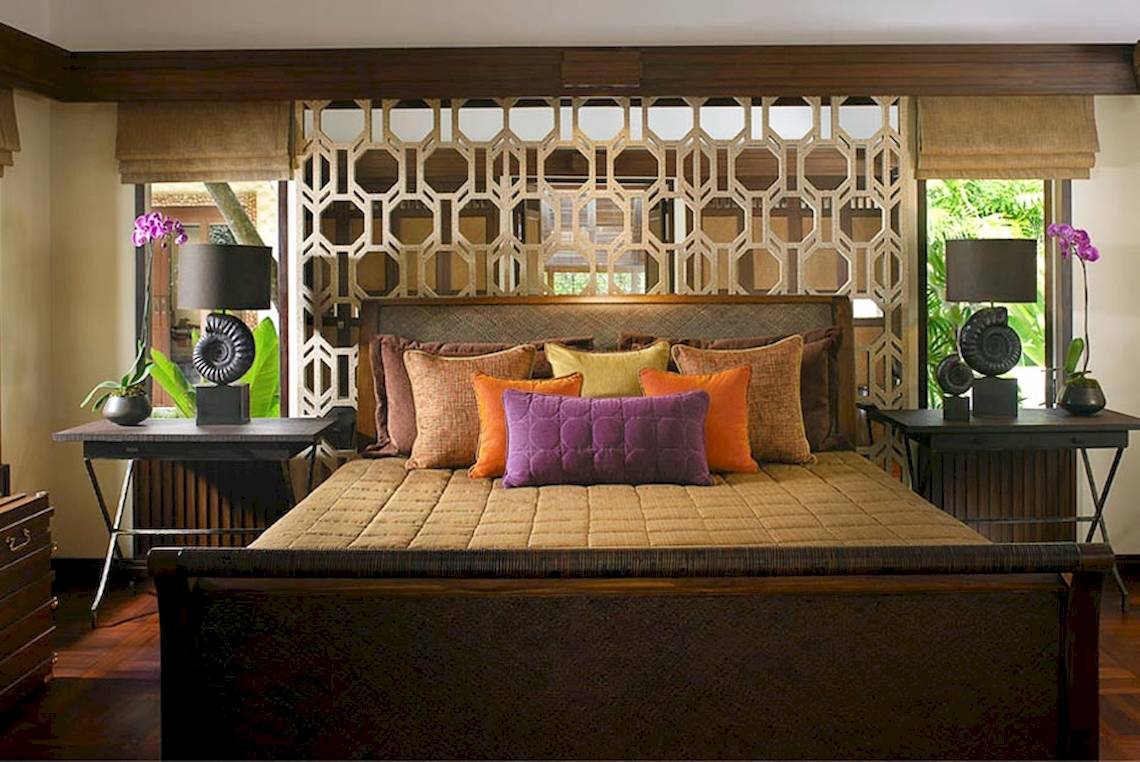 Schlafzimmer im Rayavadee Hotel mit einem großen Bett, gemusterter Wand und Nachttischen.