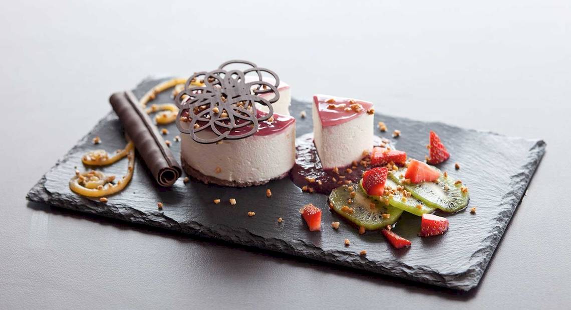 Dessertplatter im Barcelo Fuerteventura Castillo mit zwei Käsekuchen, Früchten und Schokoladenverzierungen.