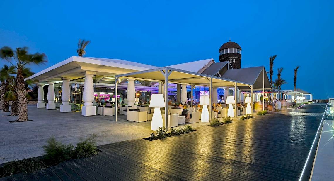 Außenbereich des Barcelo Fuerteventura Castillo Hotels bei Nacht mit Beleuchtung und Gästen.