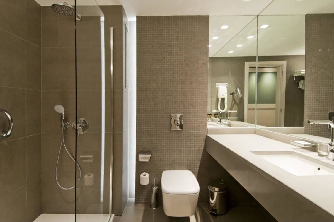 Badezimmer im Platanista Hotel mit Dusche, Toilette und Waschbecken.