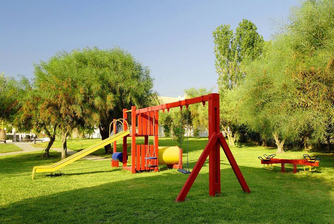 Kinderspielplatz im Platanista Hotel mit gelber Rutsche und roten Schaukeln.