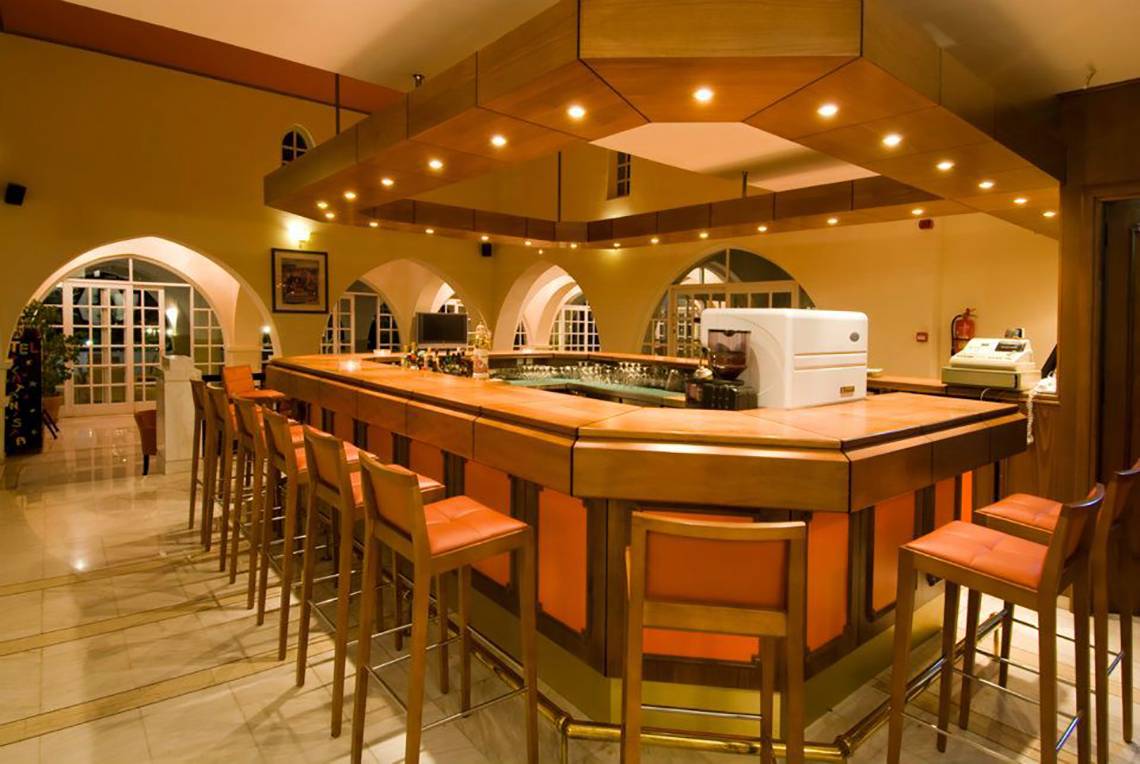 Rezeption des Platanista Hotels mit Bar und orangefarbenen Stühlen.