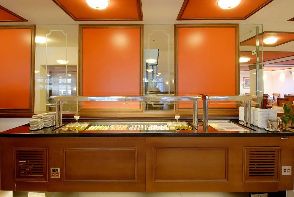 Buffetbereich im Platanista Hotel mit orangefarbenen Wänden und vielen Speisen.