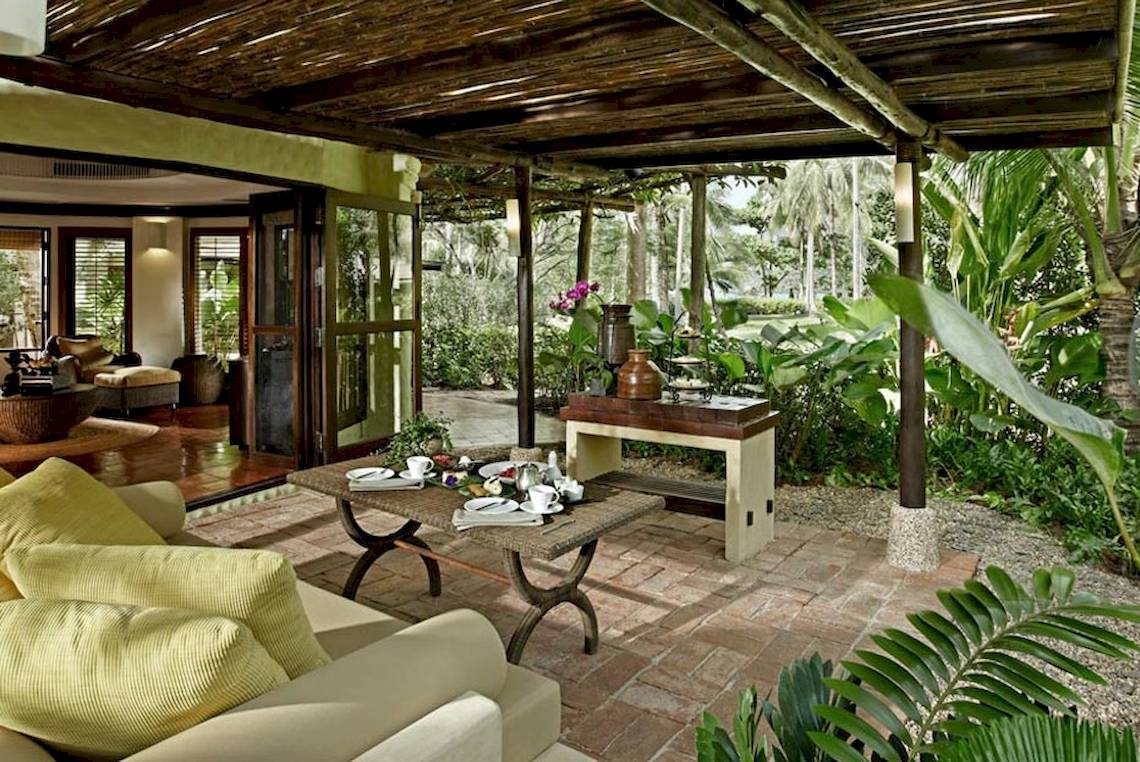 Gartensitzbereich des Rayavadee Hotels mit Tisch, Stühlen und Pflanzen.