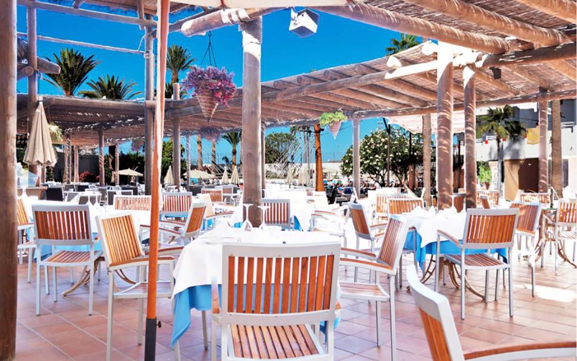 Restaurant Terrasse im Alexandre Hotel Troya mit Tischen und Stühlen unter einem Pergoladach.