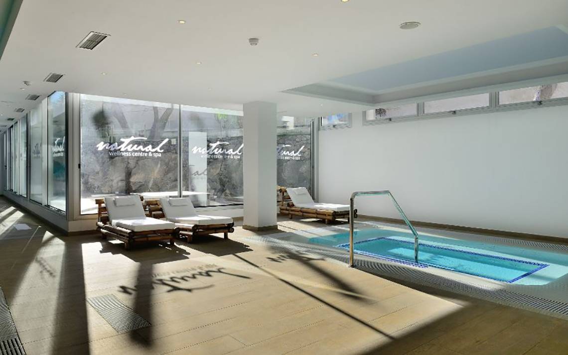 Poolbereich im Alexandre Hotel Troya mit Liegestühlen und großer Fensterfront.