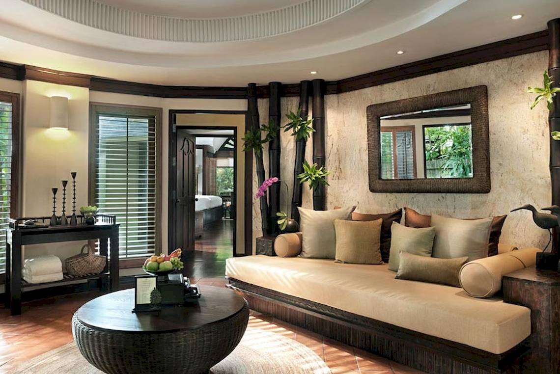 Wohnzimmer im Rayavadee Hotel mit einem großen Sofa, Kissen, einem Tisch und einem Spiegel.