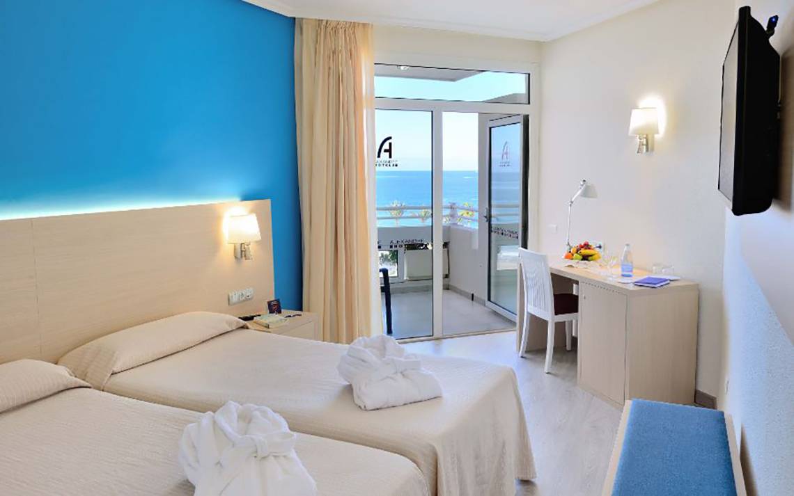 Doppelzimmer im Alexandre Hotel Troya mit Meerblick, zwei Betten, Schreibtisch und Balkon.