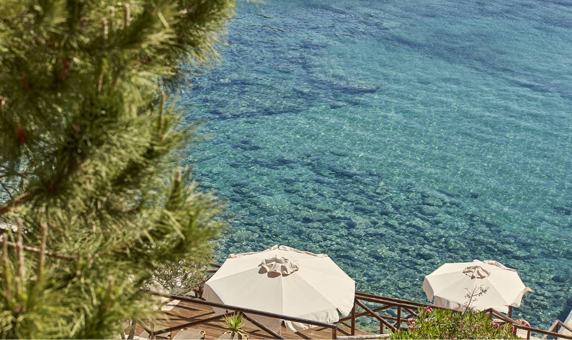 Candia Park Village Terrasse mit zwei weißen Sonnenschirmen und Blick auf das Meer.