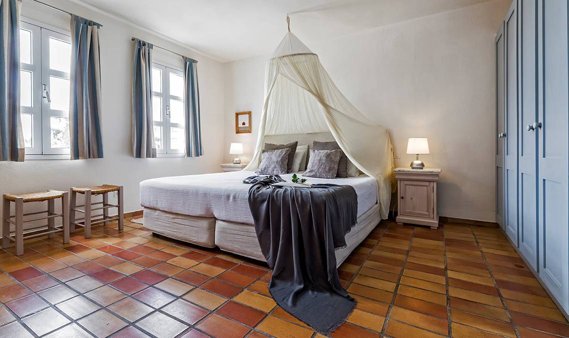 Schlafzimmer im Candia Park Village mit zwei Fenstern, zwei Nachttischen und einem Bett mit Baldachin.