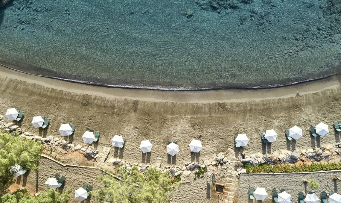Luftaufnahme von Strand und weißen Sonnenschirmen im Candia Park Village Hotel.