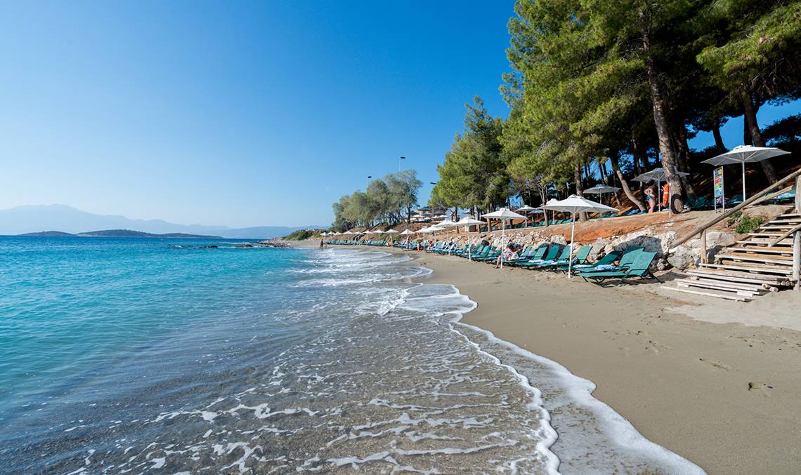 Candia Park Village Strand mit Sonnenliegen und Schirmen, klares Wasser und blauer Himmel