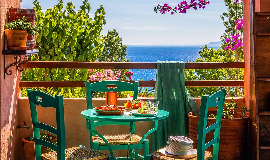 Balkon des Candia Park Village Hotels mit Blick auf das Meer und grüner Vegetation.