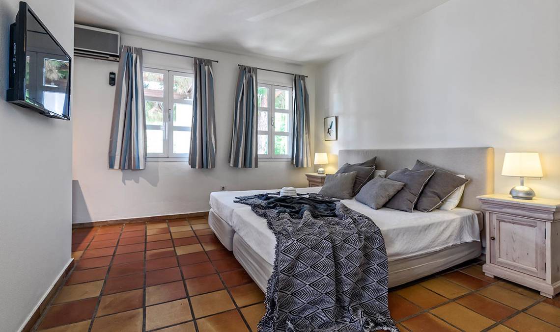 Schlafzimmer im Candia Park Village Hotel mit Doppelbett, Kissen, Decken, Nachttischen und Lampen.