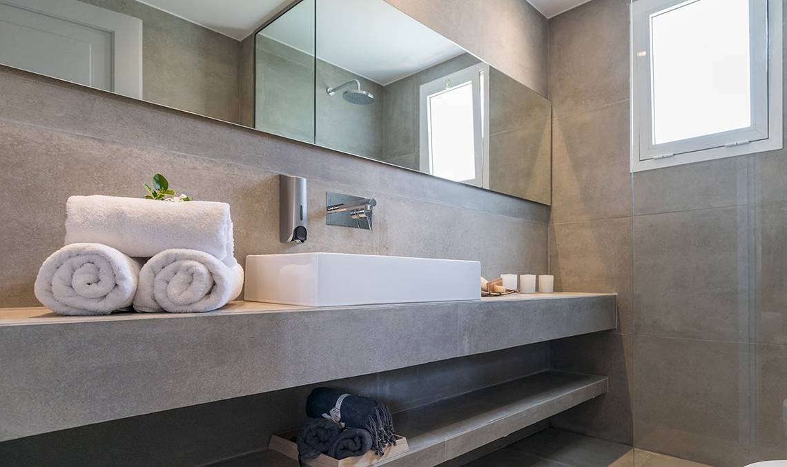 Badezimmer im Candia Park Village mit weißem Waschbecken, Handtüchern und Fliesenwänden.