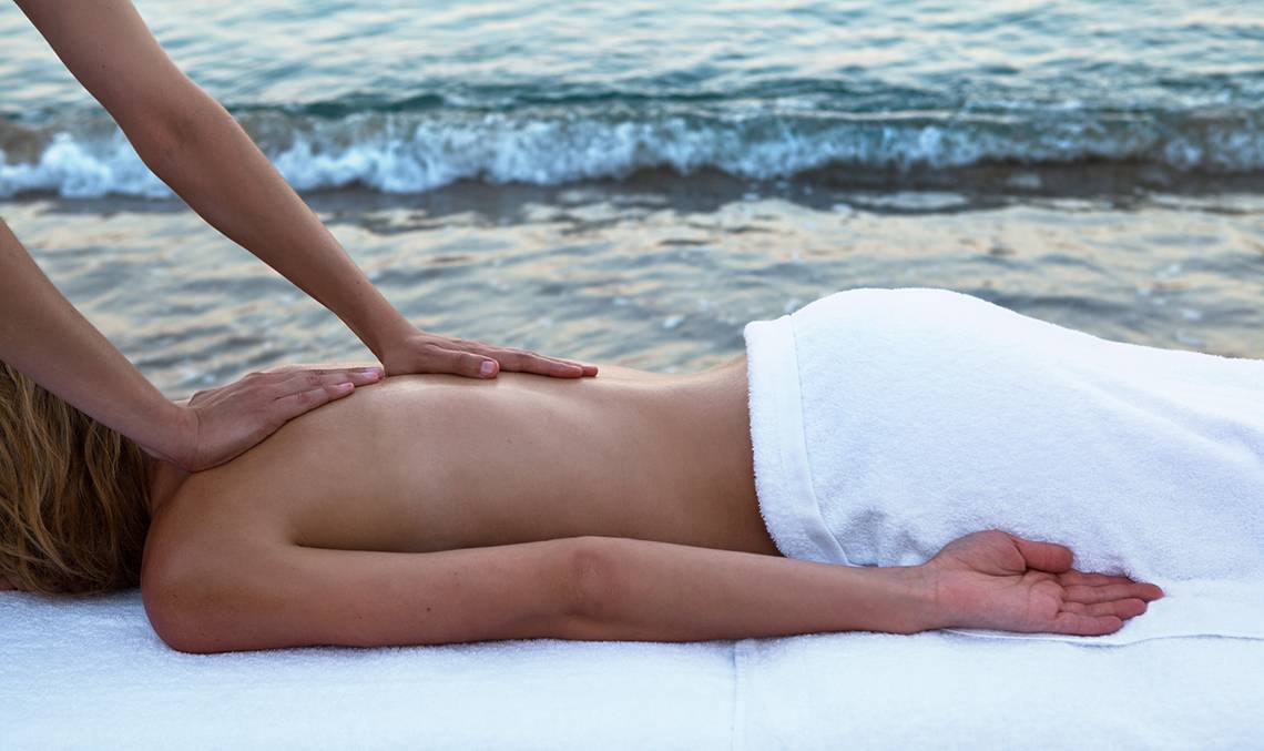 Eine Frau genießt eine Massage am Strand von Candia Park Village.