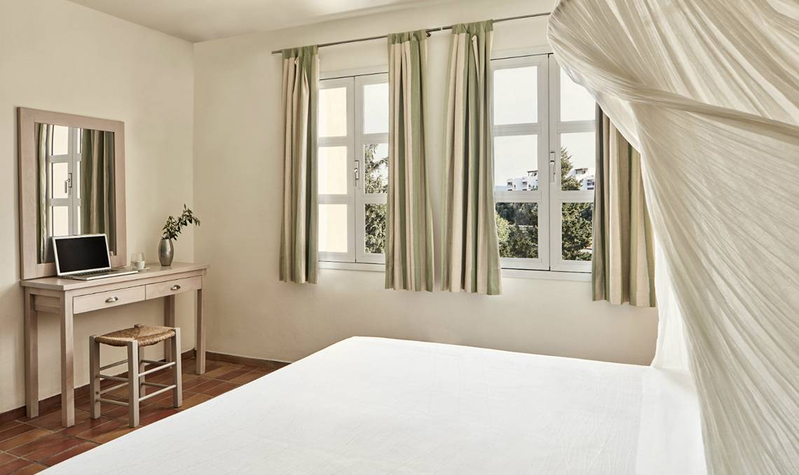 Schlafzimmer im Candia Park Village Hotel mit Bett, Nachttisch und Fenstern.