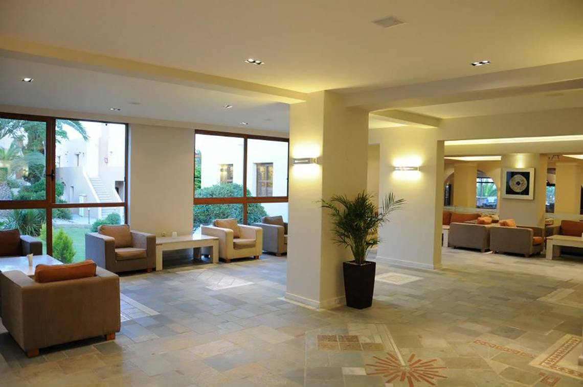 Lobby des Porto Bello Beach Hotels mit Sofas, Tischen und Pflanzen.