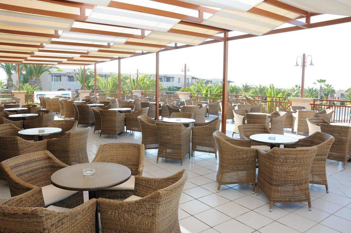 Terrasse des Porto Bello Beach Hotels mit vielen Tischen und Stühlen im Freien