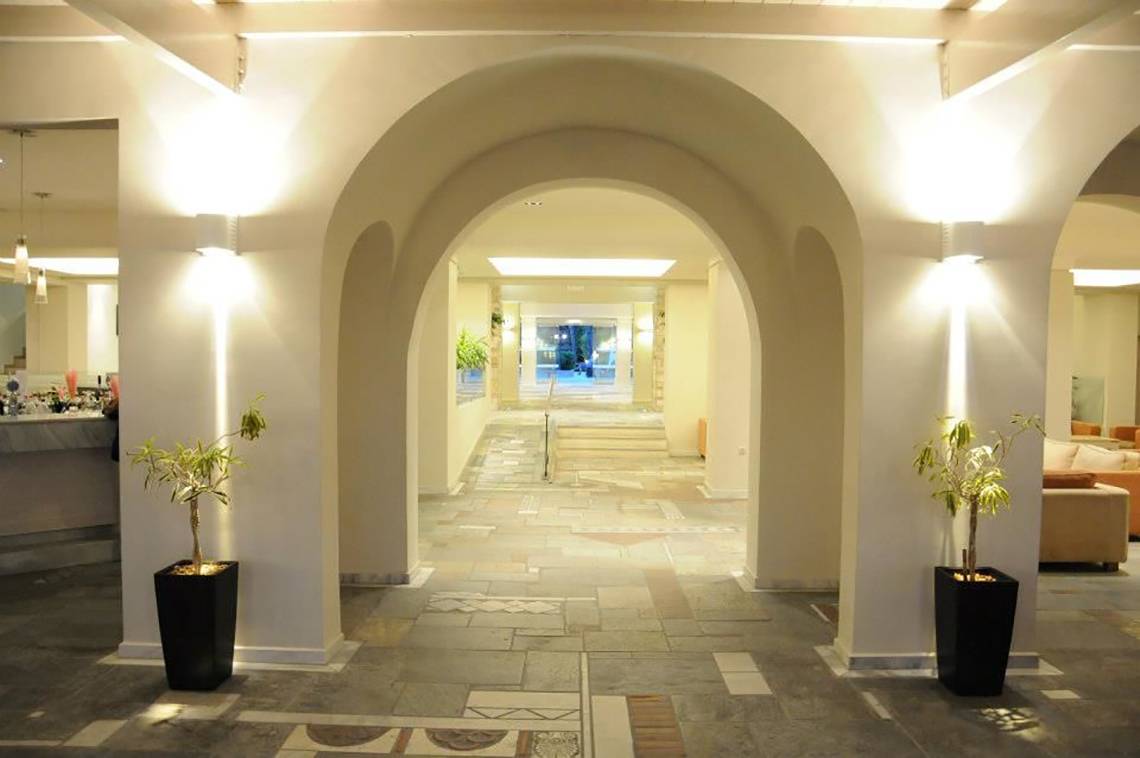 Eingangsbereich des Porto Bello Beach Hotels mit hellem, gepflastertem Boden und Bogengängen.
