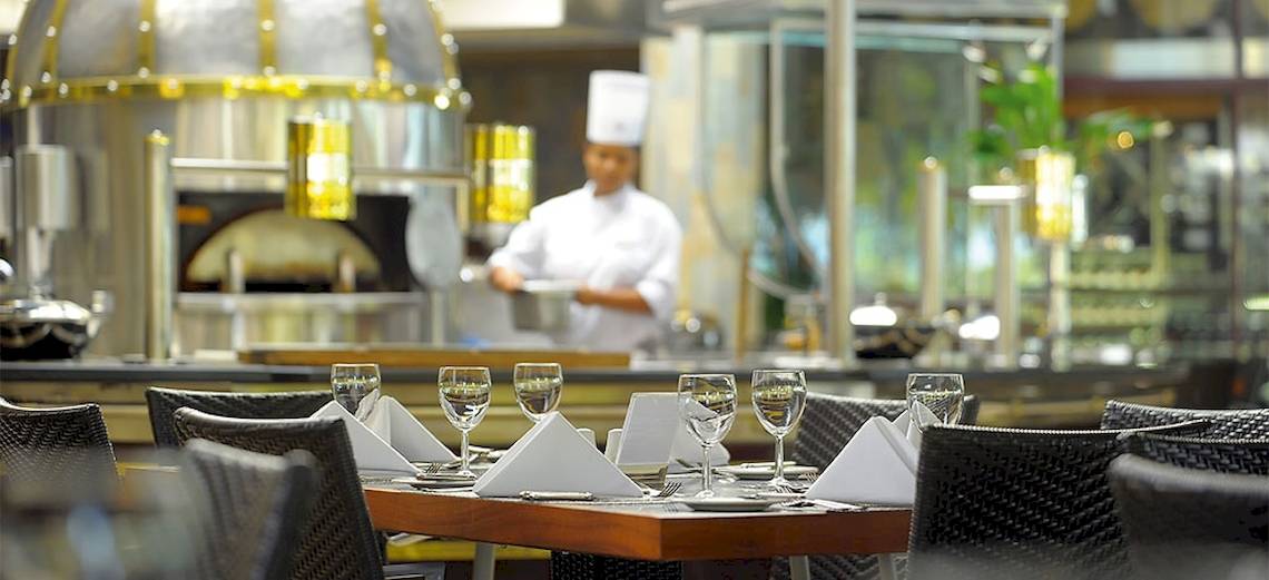 Restauranttisch im Shandrani Beachcomber Resort & Spa mit Tischwäsche und Gläsern, ein Koch im Hintergrund