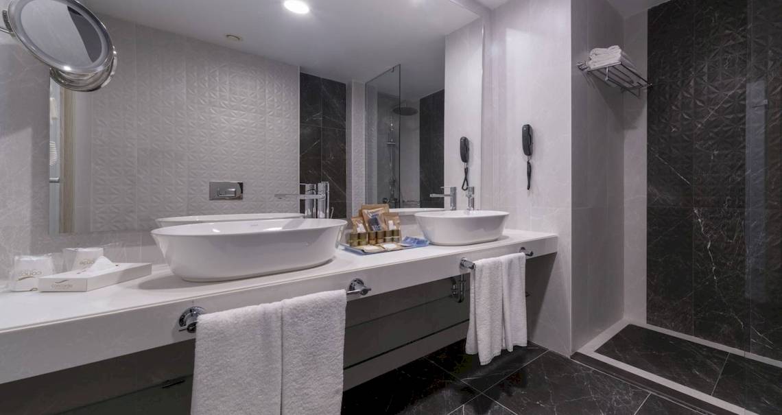 Ein Badezimmer im Concorde De Luxe Resort mit zwei Waschbecken, Spiegel und Marmorboden.