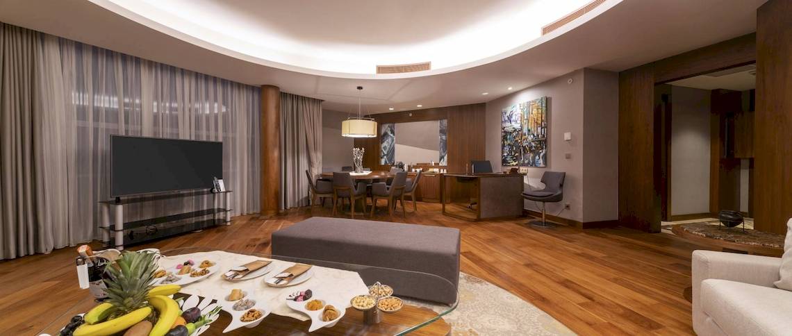 Wohnzimmer des Concorde De Luxe Resorts mit Fernseher, Esstisch und Frühstücksbuffet.