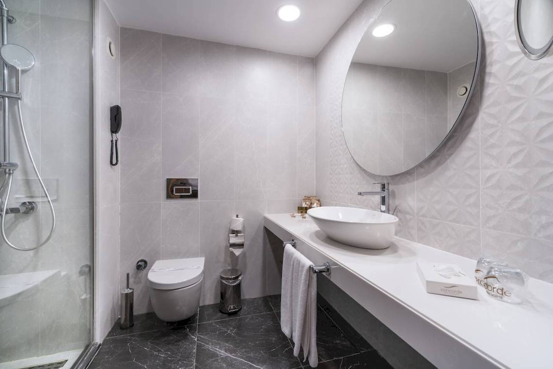 Das Badezimmer des Concorde De Luxe Resort mit einer Dusche, Toilette, Waschbecken und Spiegeln.