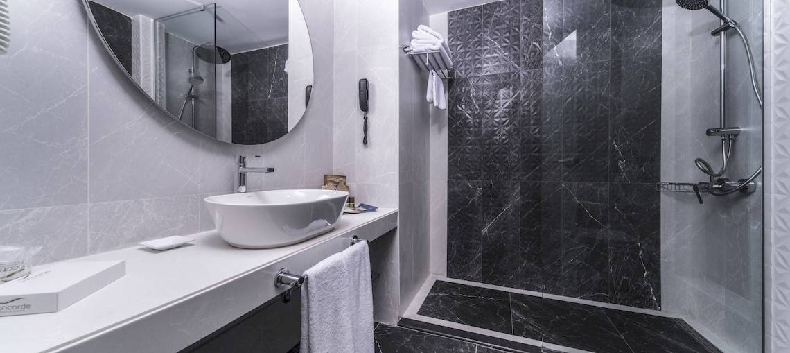 Das Badezimmer des Concorde De Luxe Resorts mit schwarzem Marmor, einer Badewanne und einer Dusche.