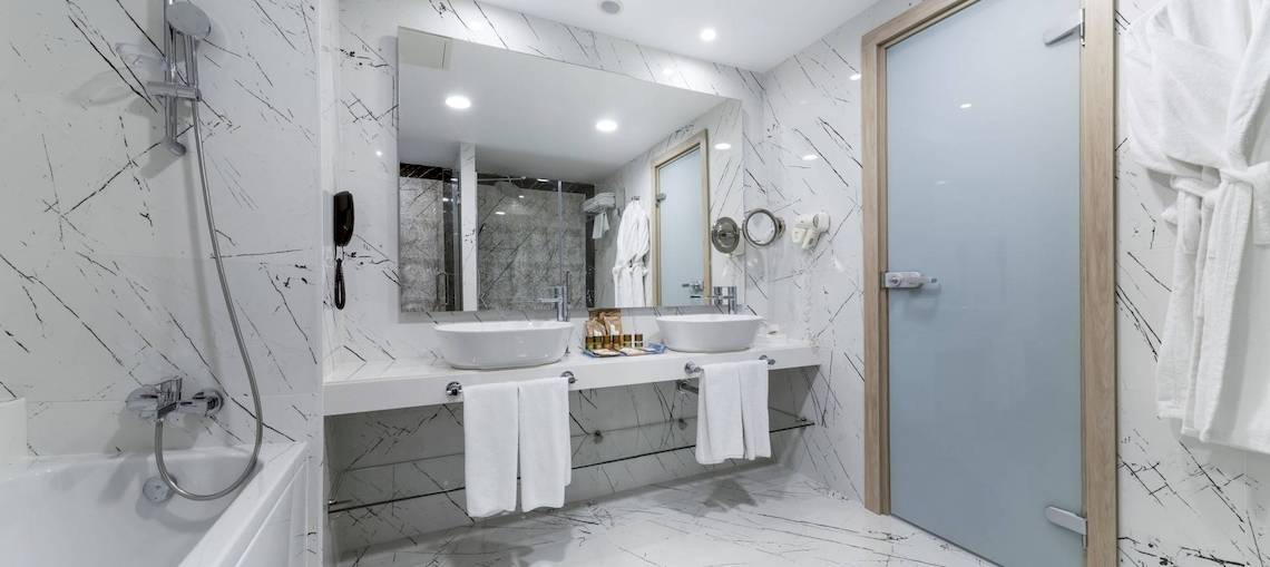 Badezimmer im Concorde De Luxe Resort mit zwei Waschbecken, Badewanne und Spiegel.