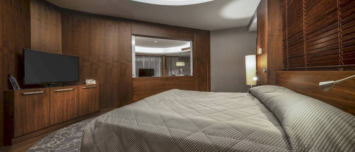 Schlafzimmer im Concorde De Luxe Resort mit Fernseher und Holzmöbeln
