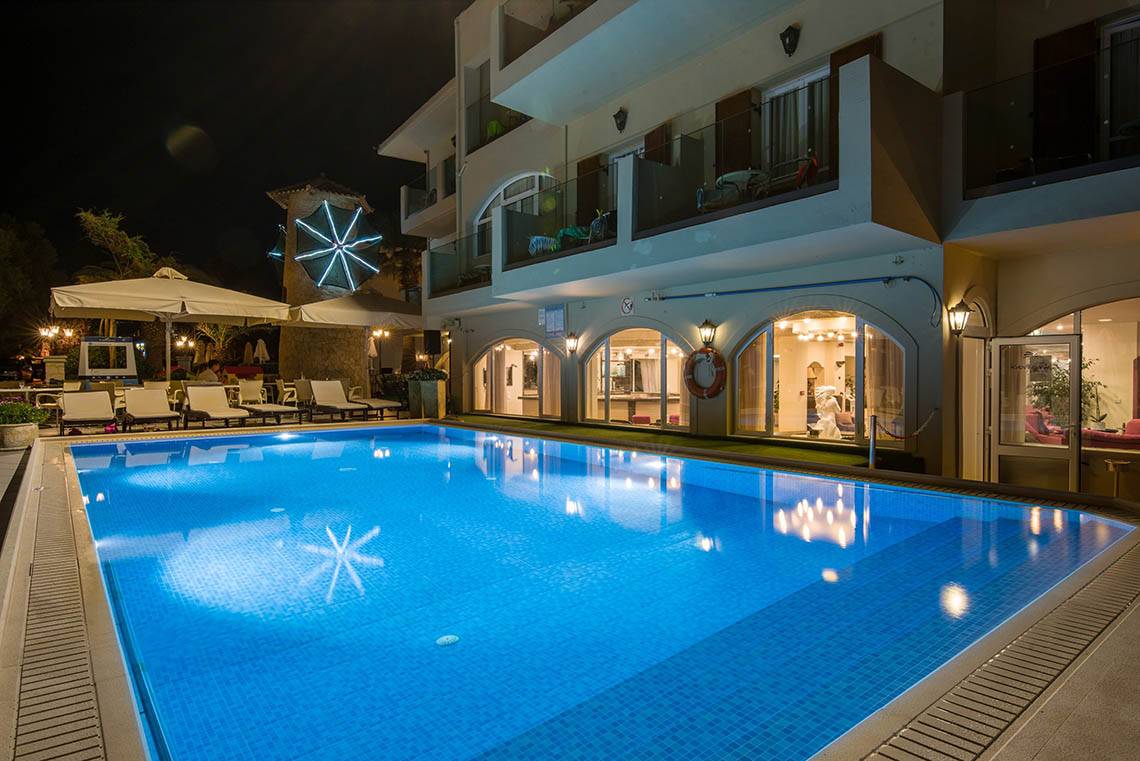 Nachtansicht des beleuchteten Pools und der Außenterrasse des Kalyves Beach Hotels.