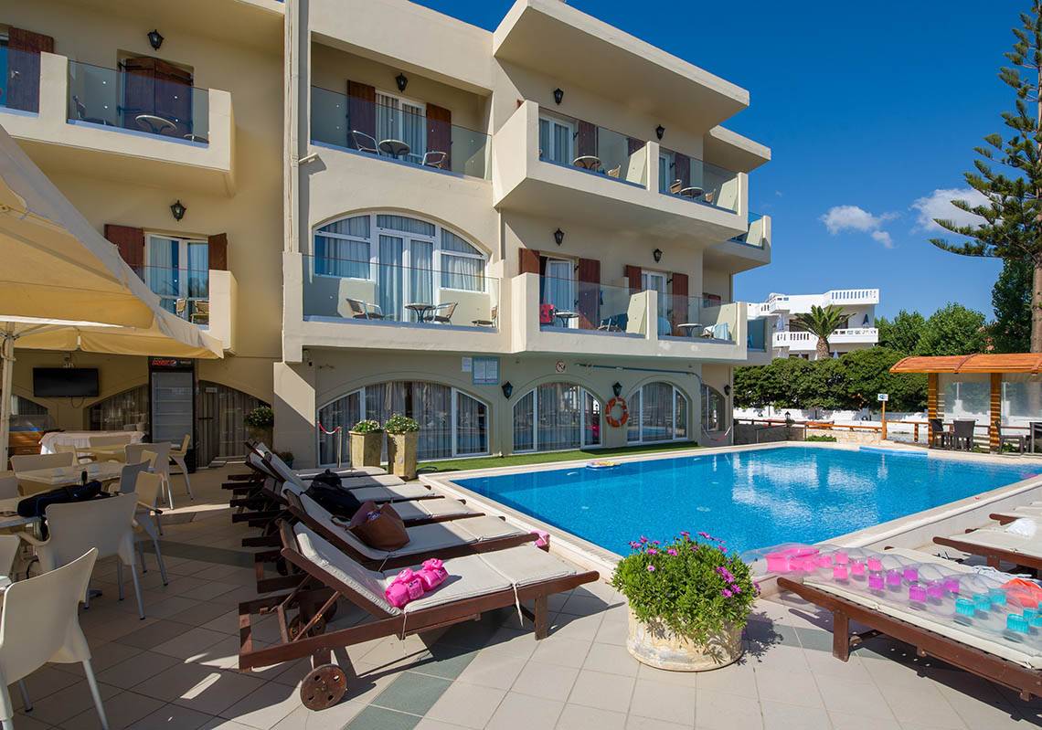 Außenbereich des Kalyves Beach Hotels mit Swimmingpool und Sonnenliegen.