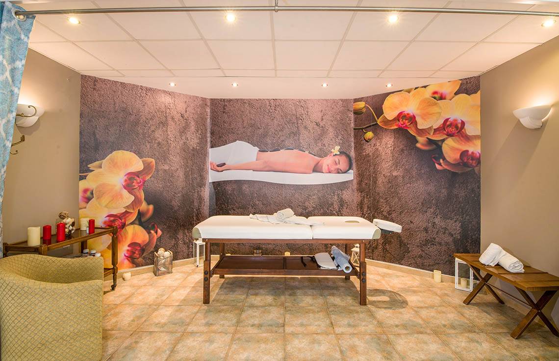 Spa-Massageraum im Kalyves Beach Hotel mit Massageliege, Deko und Wandbildern.