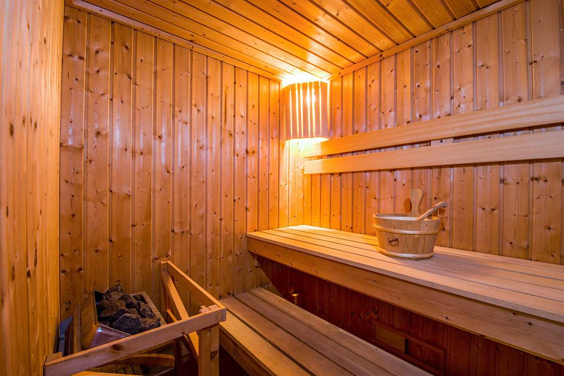 Innenansicht der Sauna im Kalyves Beach Hotel mit Holzwänden, Bänken und einem Holzfass.