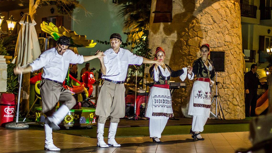Ein Paar tanzt traditionell auf der Bühne im Freien des Kalyves Beach Hotels.