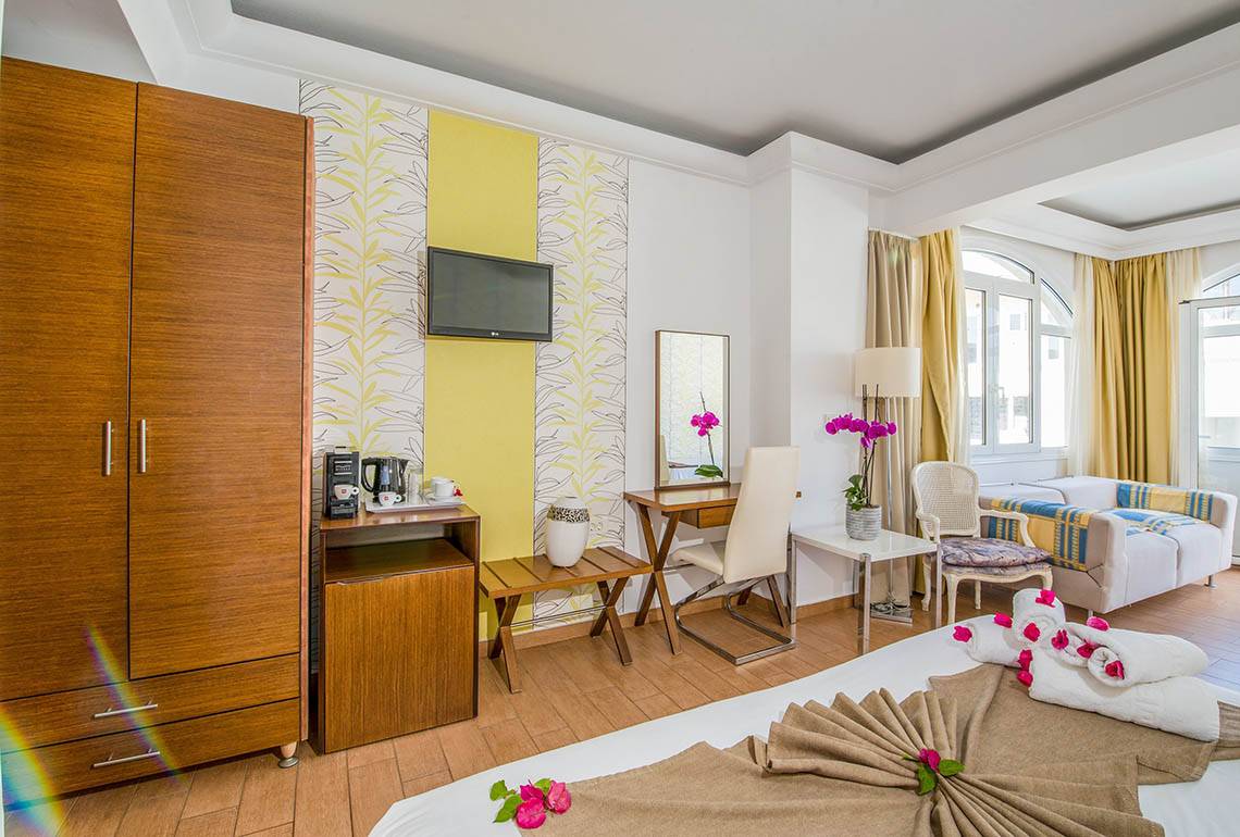 Innenansicht eines Zimmers im Kalyves Beach Hotel mit Bett, Schreibtisch, Fernseher und Möbeln.