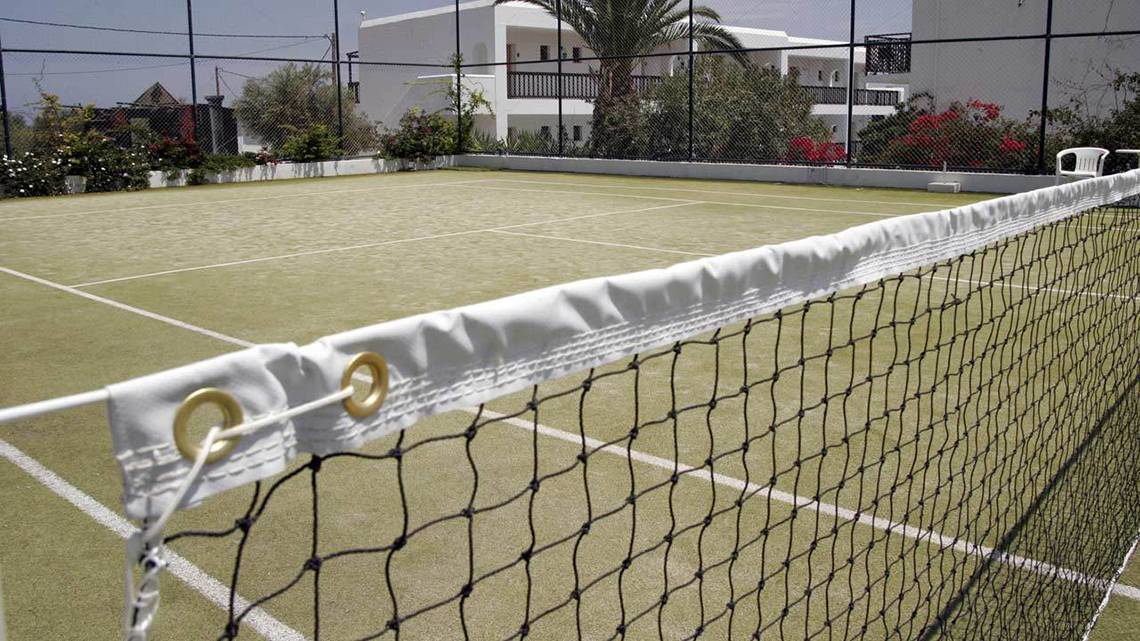 Tennisplatz im Hersonissos Maris Hotel, umgeben von Gebäuden und Pflanzen.