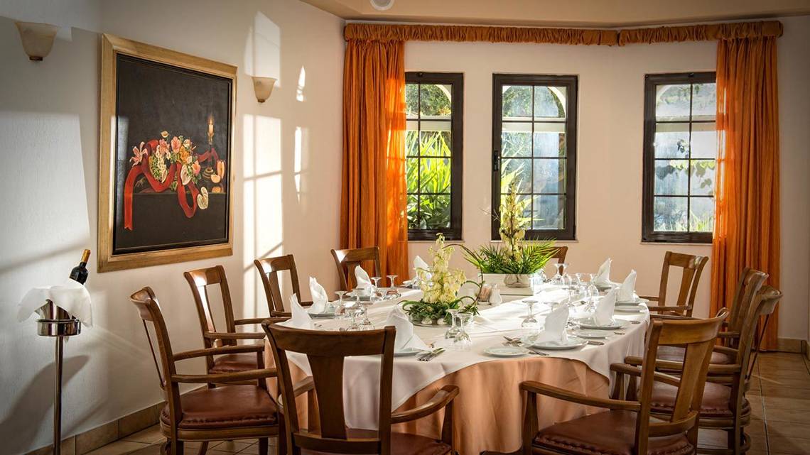 Ein formelles Esszimmer im Hersonissos Maris Hotel mit Tisch, Stühlen und Dekor.