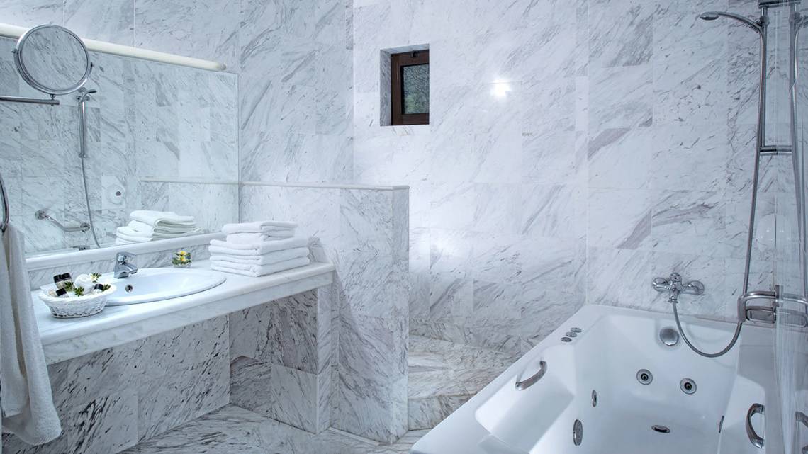 Badezimmer im Hersonissos Maris Hotel mit weißen Marmorfliesen und einer Badewanne.