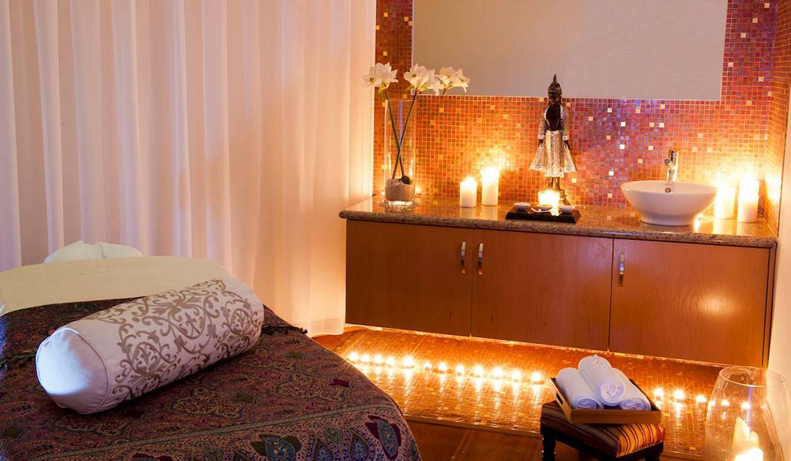 Spa-Behandlungsraum im Pioneer Beach Hotel mit Kerzen, einem Waschbecken und einem Bett.