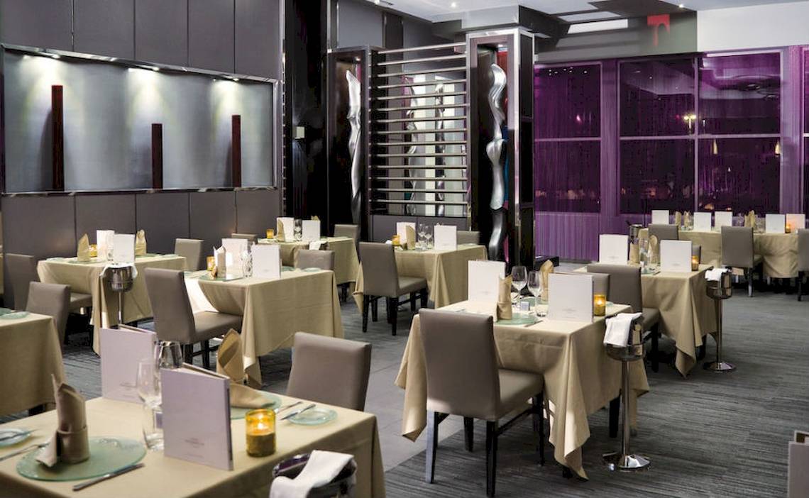 Innenansicht des Riu Palace Peninsula Restaurants mit gedeckten Tischen und Stühlen.