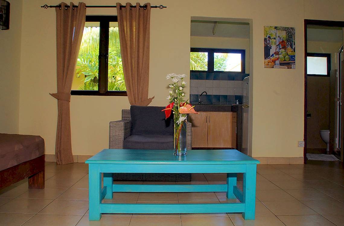 Wohnzimmer im Anelia Resort & Spa mit blauem Tisch, Blumenvase und Wohnzimmermöbeln.