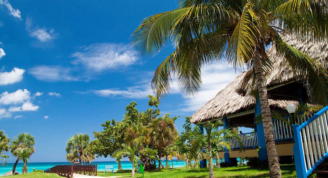 Ein Hotel mit Palmen und blauem Himmel im Hintergrund.