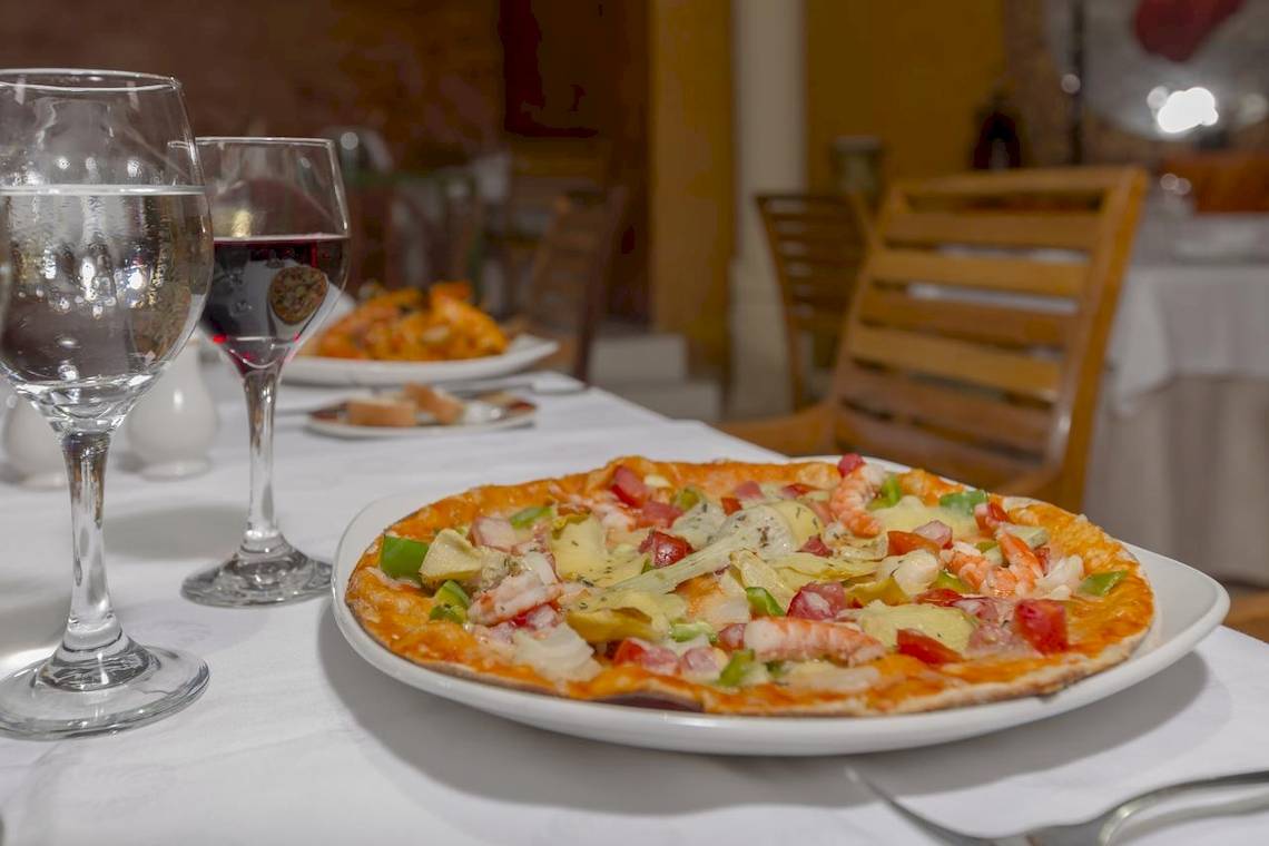 Essen im Hotelrestaurant Melia Las Antillas mit Pizza, Wein und Wasser.